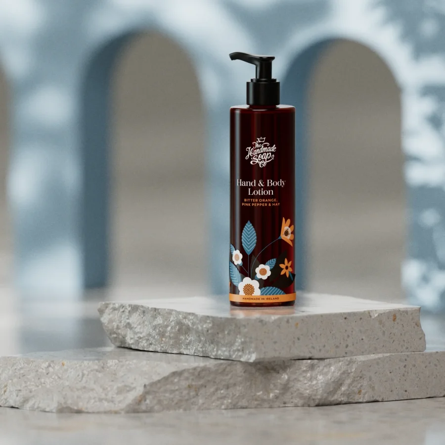 Flasche der Bitter Orange & Pink Pepper Bodylotion 250 ml von The Handmade Soap Company auf hellem Hintergrund