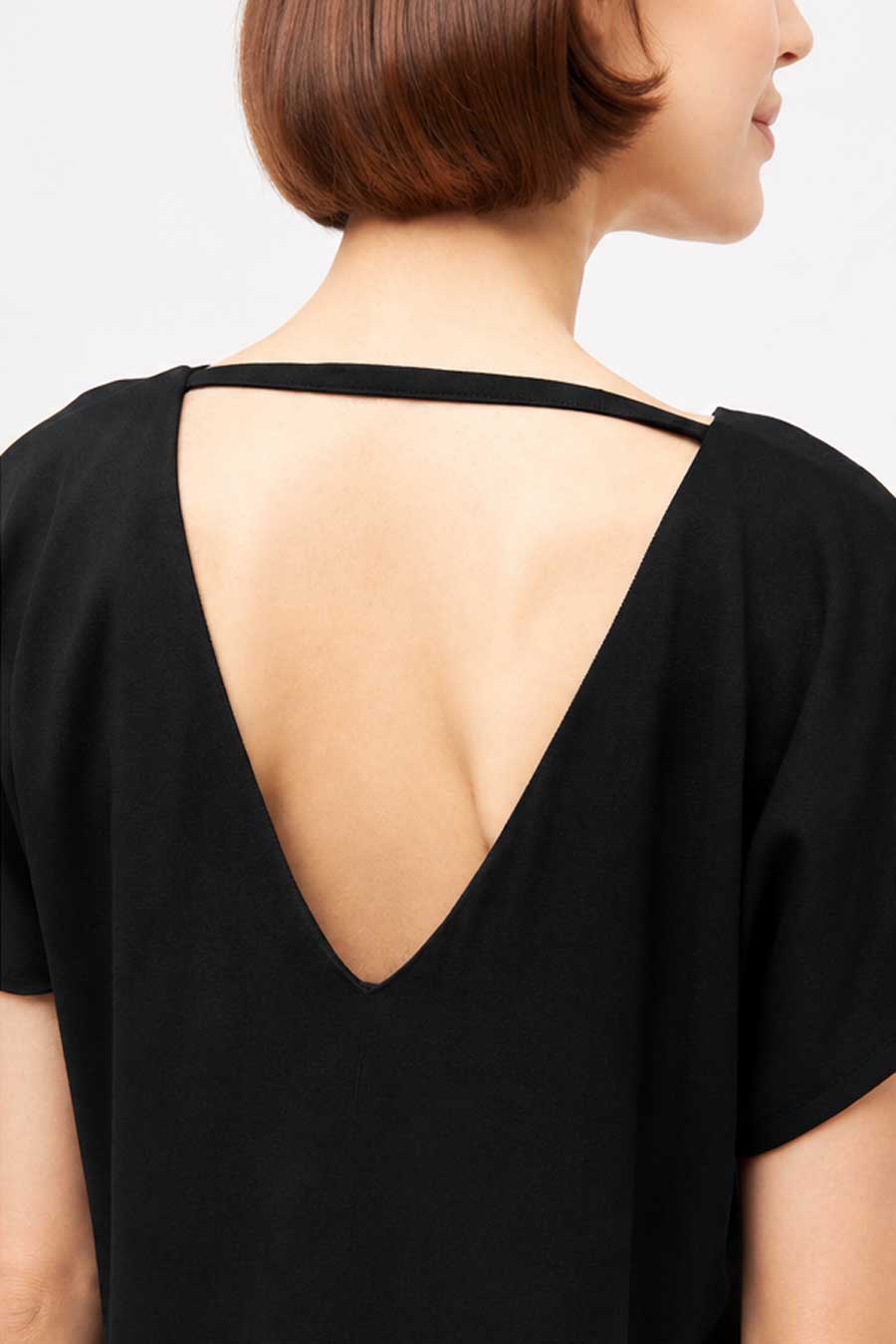 schwarzes Kleid CARO aus TENCEL Mit V-Ausschnitt vorn und hinten. Detailansicht Rückenausschnitt. Das Kleid ist gerade geschnitten, knielang, mit Seitentaschen in der Naht.