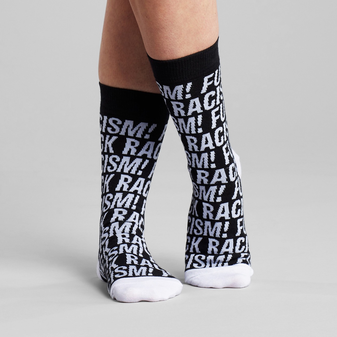 Socken mit Fuck Racism Slogan von Dedicated. Strümpfe aus Bio-Baumwolle in Schwarz mit weißem Muster.