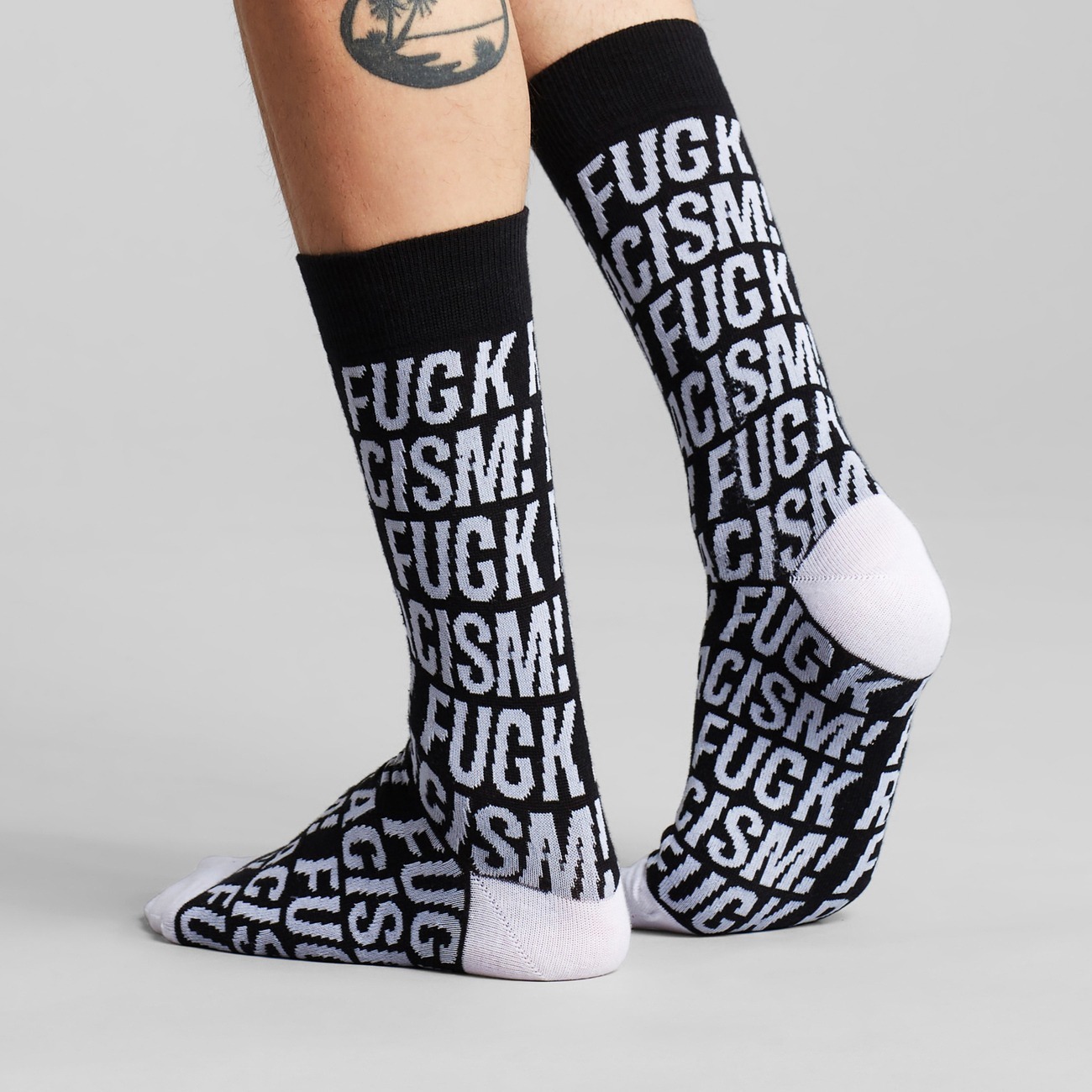 Socken mit Fuck Racism Slogan von Dedicated. Strümpfe aus Bio-Baumwolle in Schwarz mit weißem Muster.