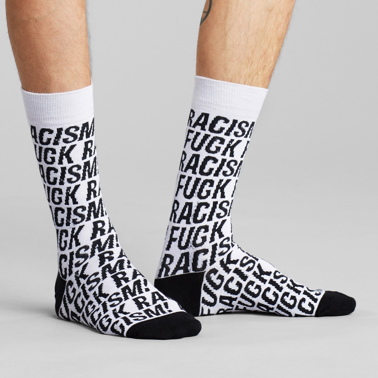 Socken mit Fuck Racism Slogan von Dedicated. Strümpfe aus Bio-Baumwolle in Weiß mit schwarzem Muster.