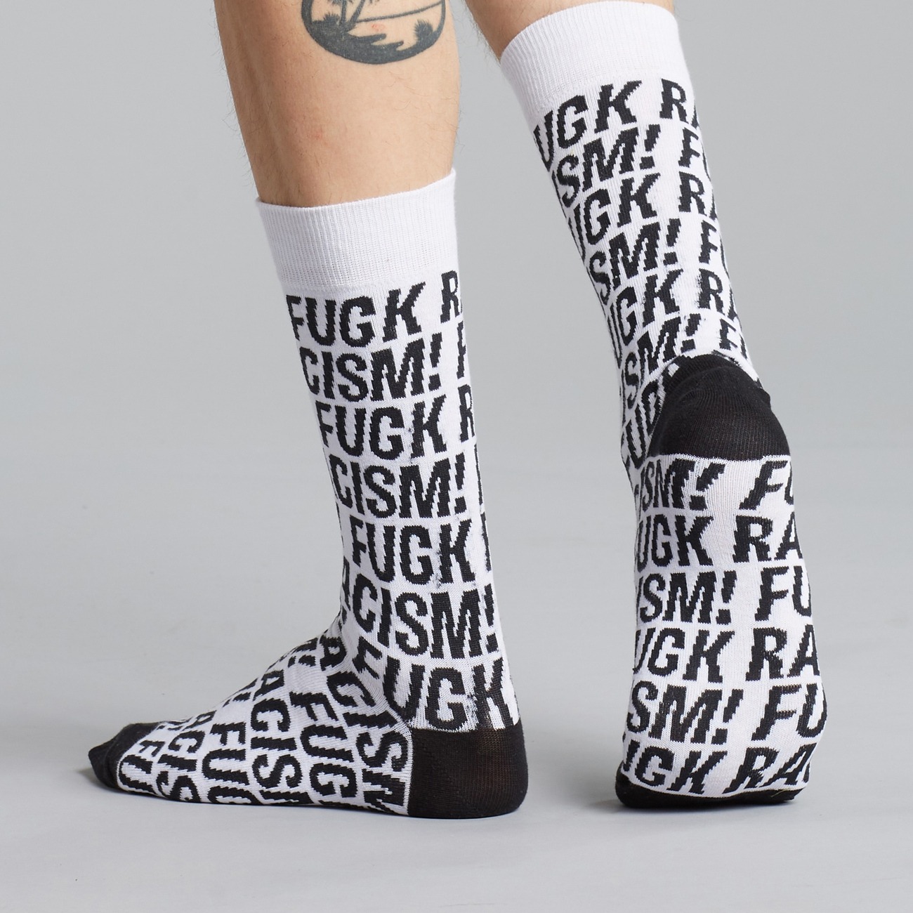 Socken mit Fuck Racism Slogan von Dedicated. Strümpfe aus Bio-Baumwolle in Weiß mit schwarzem Muster.