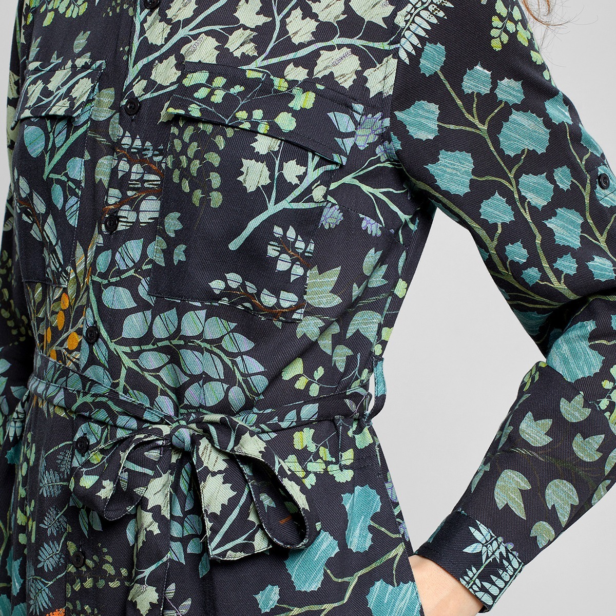 Schwarzes mit grünen Blättern bedrucktes Hemdblusenkleid von Dedicated aus 100% TENCEL™ Lyocell. Mit Hüfttaschen, Taillengürtel und durchgehender Knopfleiste.